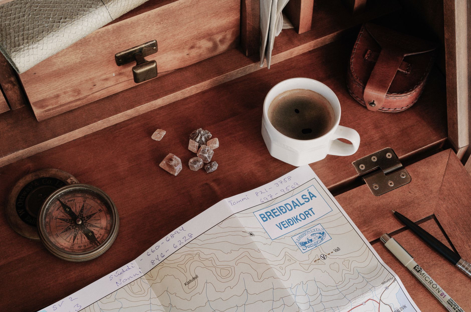 Travel journal notebook resting beside compass on weathered wood desk