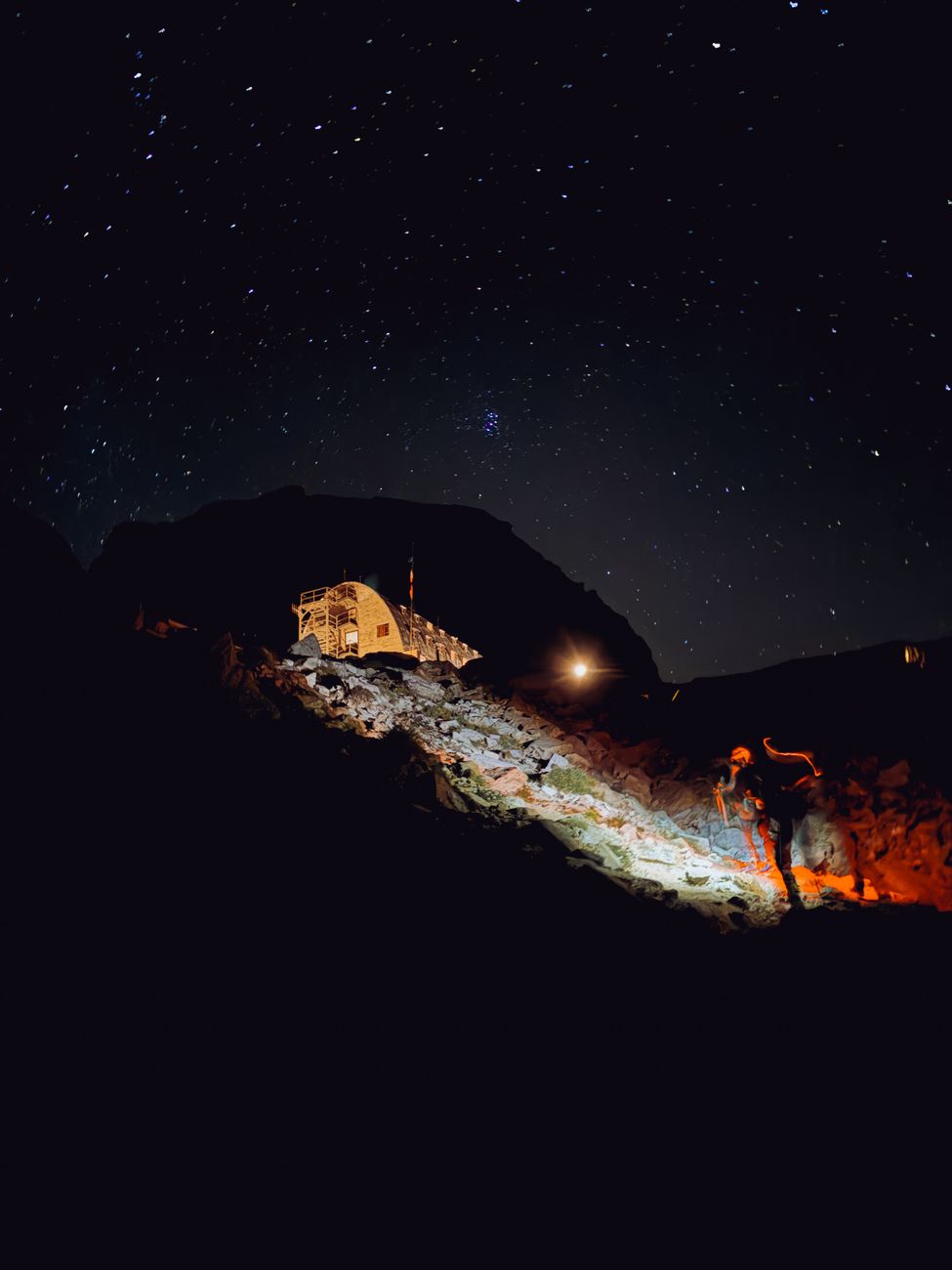 High altitude mountain hut under starlit night sky in Alps
